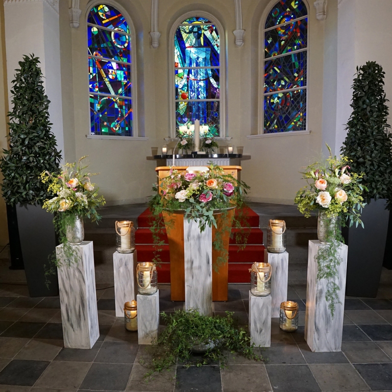 floraler Trauerdekor für Urne auf Säulen in der Kapelle, Blumenschmuck mit Rosen als Urnenkranz und Blumenstrauß in Vasen